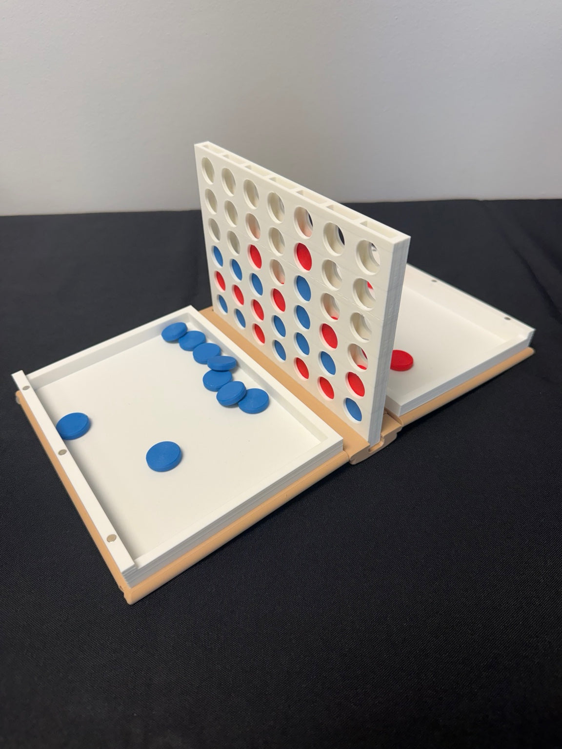 Four-in-a-row book game with upright grid and disc trays