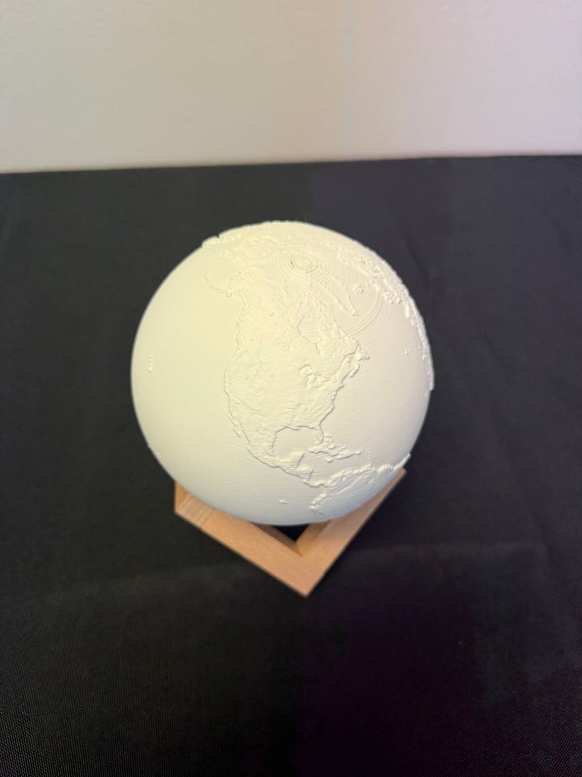 White globe light with raised continents on a triangular stand
