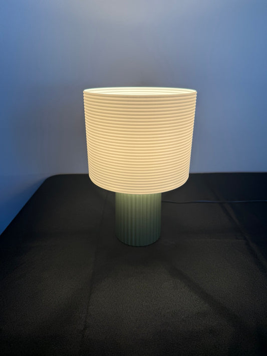 Ribbed cream and green table lamp illuminated